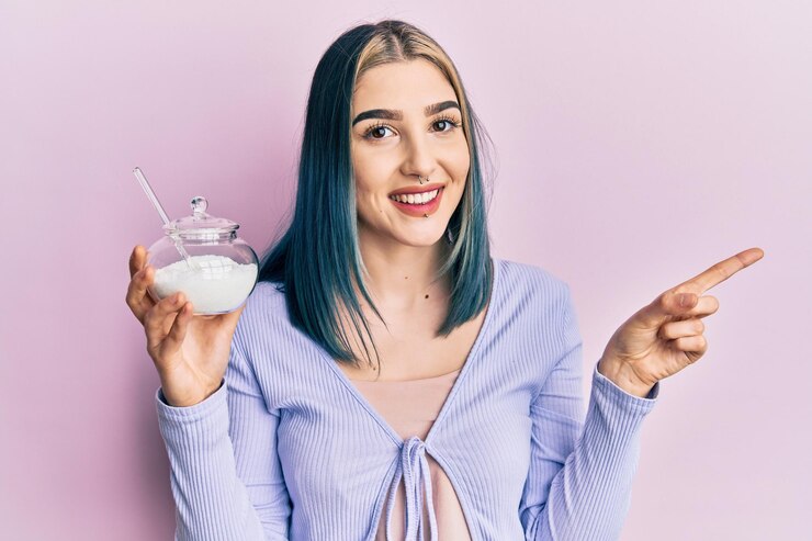 young-modern-girl-holding-bowl-with-sugar-smiling-happy-pointing-with-hand-finger-side_839833-11207