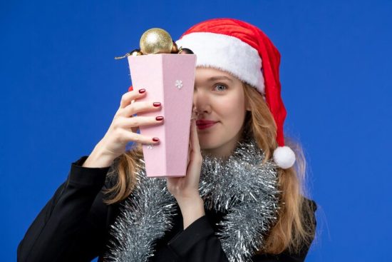 front-view-young-woman-with-new-year-s-tree-toys-blue-wall_140725-120520