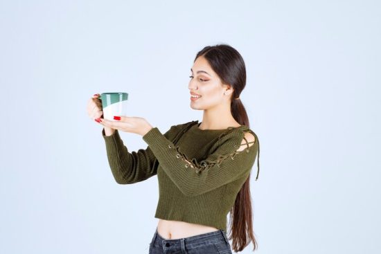 young-pretty-woman-model-holding-cup-drink-standing_144627-56078