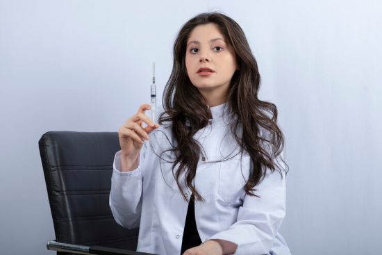 portrait-female-doctor-medical-mask-white-coat-holding-syringe_114579-36798