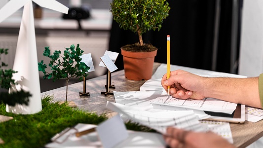 side-view-man-working-eco-friendly-wind-power-project-with-paper-plans