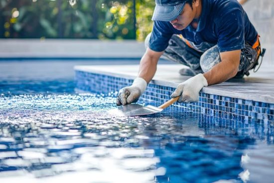 asian-man-construction-worker-using-trowel-building-spatula-spreading-cement-grout-blue-ceramic-tile